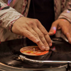 Nachaufnahme eines Plattentellers mit den Händen eines DJs